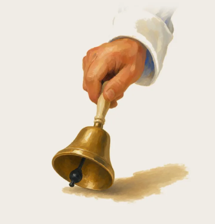 A hand ringing a small brass bell.